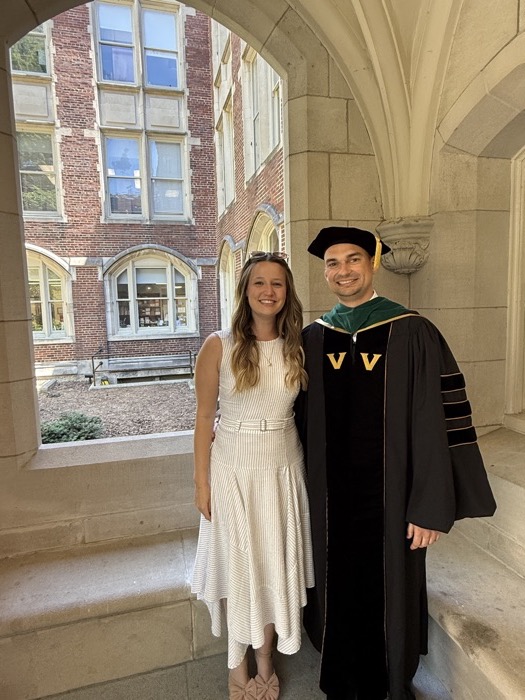 Michal and Austin at a graduation under stone arches